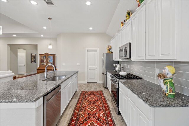 kitchen with white cabinets, sink, appliances with stainless steel finishes, and an island with sink