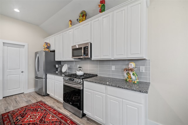 kitchen featuring backsplash, white cabinets, vaulted ceiling, and appliances with stainless steel finishes