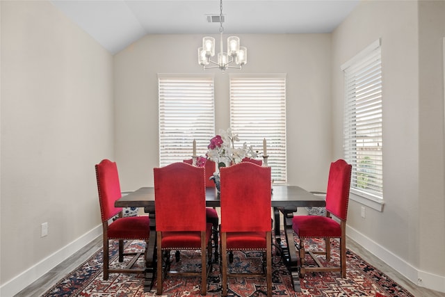 dining room with a notable chandelier, plenty of natural light, hardwood / wood-style flooring, and vaulted ceiling