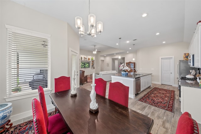 dining area with ceiling fan with notable chandelier, light wood-type flooring, and sink