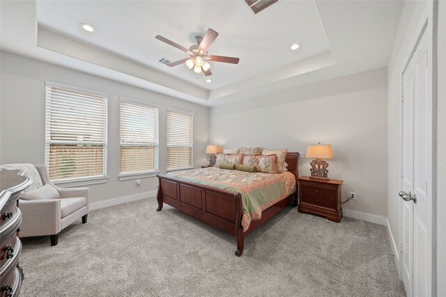 carpeted bedroom featuring ceiling fan, a raised ceiling, and a closet