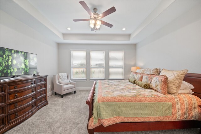 carpeted bedroom featuring ceiling fan and a raised ceiling