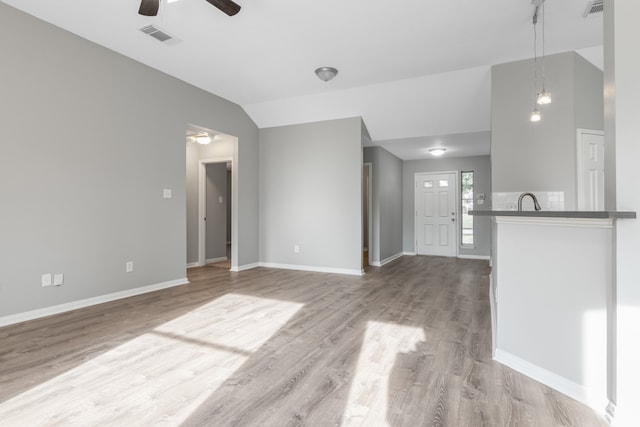 unfurnished living room with ceiling fan, lofted ceiling, sink, and light hardwood / wood-style flooring