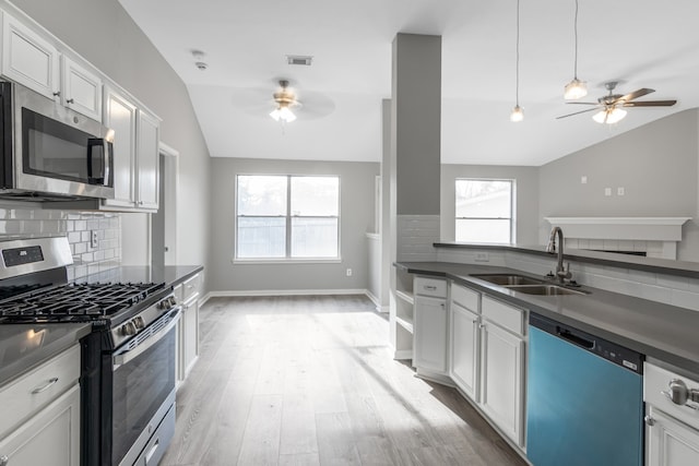 kitchen with stainless steel appliances, vaulted ceiling, sink, white cabinets, and plenty of natural light