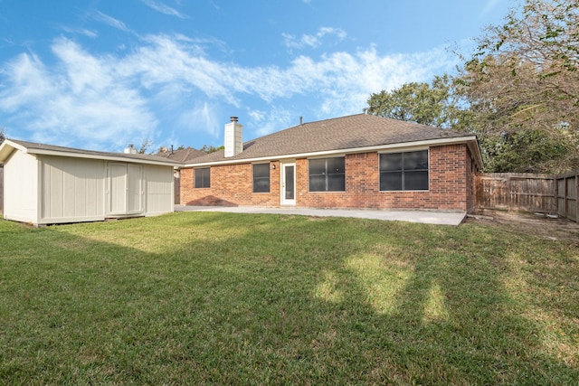 back of house with a storage unit and a lawn