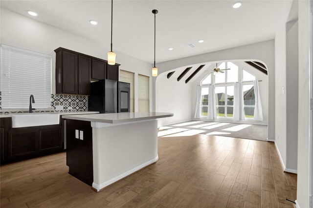 kitchen featuring black refrigerator, light wood-type flooring, sink, pendant lighting, and a center island