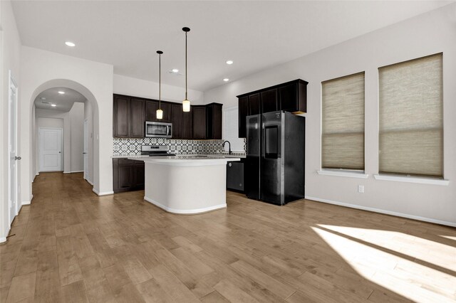 kitchen with a kitchen island, stainless steel appliances, hanging light fixtures, and light hardwood / wood-style flooring