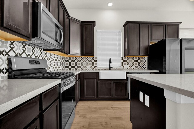 kitchen with backsplash, light stone countertops, stainless steel appliances, and light wood-type flooring