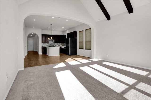 kitchen with hanging light fixtures, backsplash, light hardwood / wood-style floors, a kitchen island, and appliances with stainless steel finishes