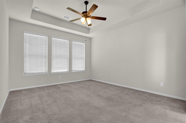 carpeted spare room featuring ceiling fan and a tray ceiling