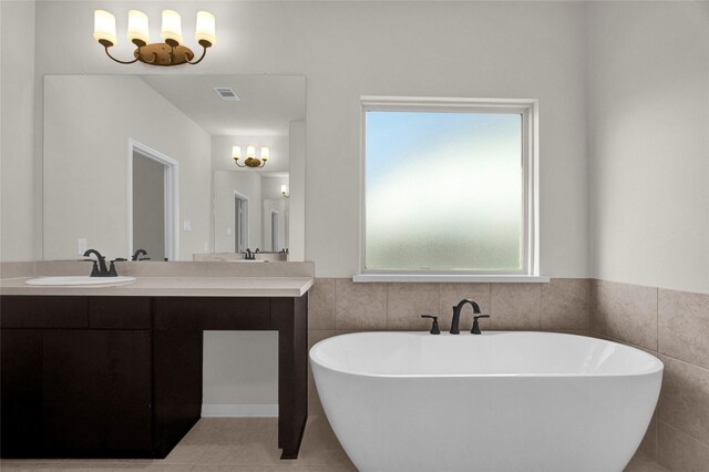 bathroom with a washtub, vanity, tile patterned floors, and a wealth of natural light