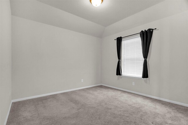 carpeted spare room featuring vaulted ceiling