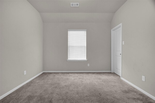 carpeted empty room featuring vaulted ceiling