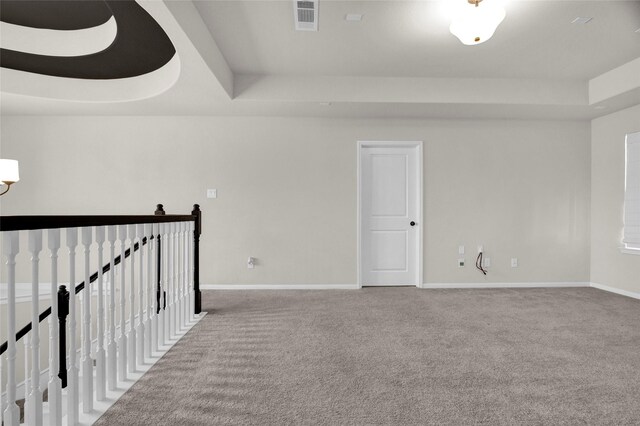 spare room with carpet flooring and a raised ceiling