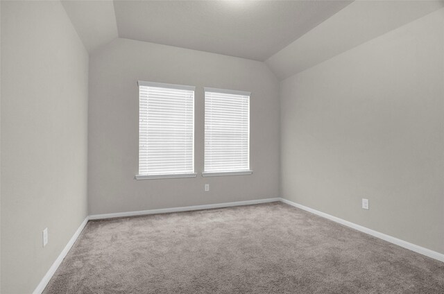 carpeted empty room featuring vaulted ceiling