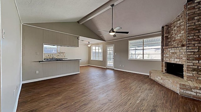 unfurnished living room featuring ceiling fan, vaulted ceiling with beams, dark hardwood / wood-style floors, a textured ceiling, and a fireplace