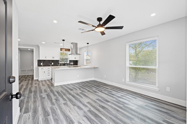 unfurnished living room featuring plenty of natural light, light hardwood / wood-style floors, sink, and ceiling fan