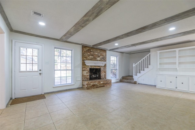 unfurnished living room with beamed ceiling, a wealth of natural light, a fireplace, and light tile patterned flooring