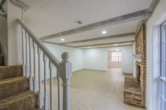 basement with light tile patterned flooring, a textured ceiling, and a brick fireplace