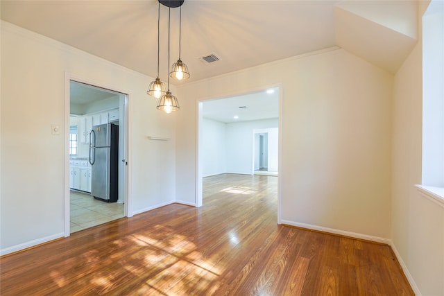 unfurnished dining area with hardwood / wood-style floors and ornamental molding