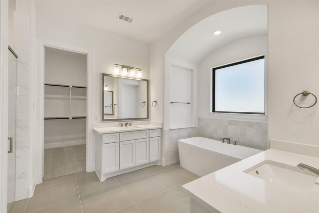 12926 Whitewater Way, Conroe, TX 77302 - bathroom featuring two vanities, tile patterned flooring, a freestanding bath, a walk in closet, and a stall shower
