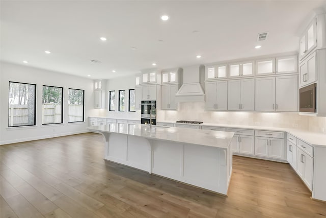 12926 Whitewater Way, Conroe, TX 77302 - kitchen featuring premium range hood, stainless steel appliances, light countertops, a large island, and decorative backsplash