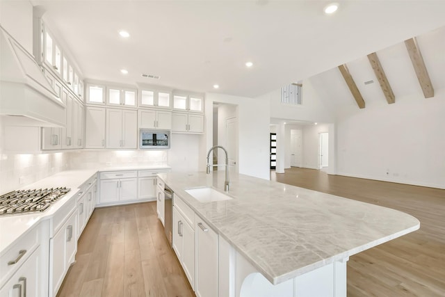 12926 Whitewater Way, Conroe, TX 77302 - kitchen with appliances with stainless steel finishes, custom range hood, white cabinets, light wood-style floors, and decorative backsplash