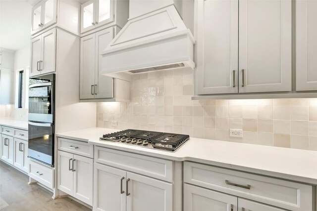 12926 Whitewater Way, Conroe, TX 77302 - kitchen featuring stainless steel appliances, custom exhaust hood, light countertops, backsplash, and white cabinetry