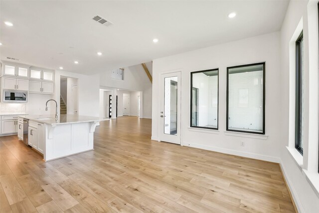 12926 Whitewater Way, Conroe, TX 77302 - kitchen with built in microwave, open floor plan, white cabinets, light countertops, and light wood-style flooring