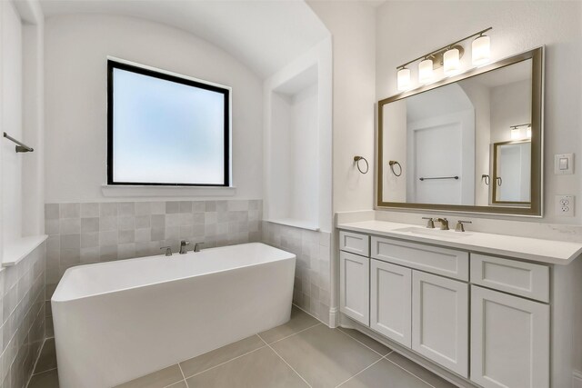 12926 Whitewater Way, Conroe, TX 77302 - bathroom featuring tile walls, a soaking tub, tile patterned floors, vanity, and a wainscoted wall
