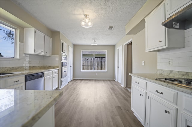 kitchen with white cabinetry, stainless steel appliances, backsplash, a textured ceiling, and light wood-type flooring