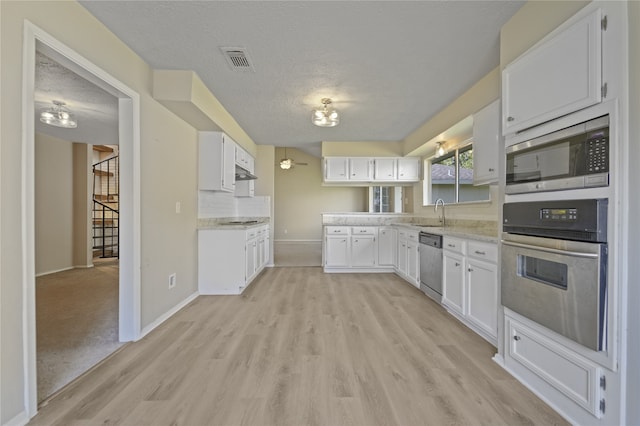 kitchen featuring white cabinets, stainless steel appliances, and a textured ceiling