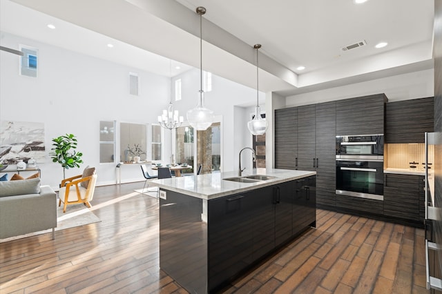 kitchen with decorative light fixtures, sink, a breakfast bar, and an island with sink