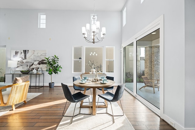 dining space with a towering ceiling, dark hardwood / wood-style floors, and a notable chandelier