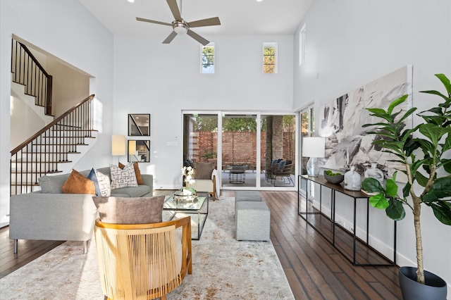 living room featuring ceiling fan, dark hardwood / wood-style floors, and a towering ceiling