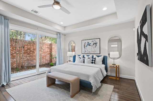 bedroom featuring access to outside, ceiling fan, dark hardwood / wood-style flooring, and a tray ceiling