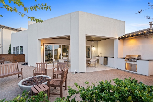 back house at dusk featuring a patio area and exterior kitchen