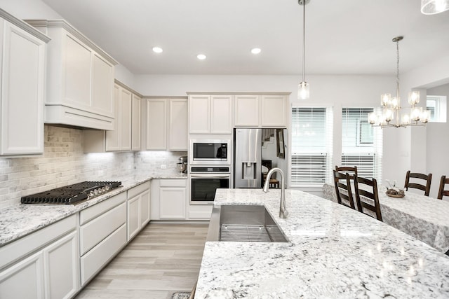 kitchen with an inviting chandelier, sink, light hardwood / wood-style flooring, decorative light fixtures, and stainless steel appliances