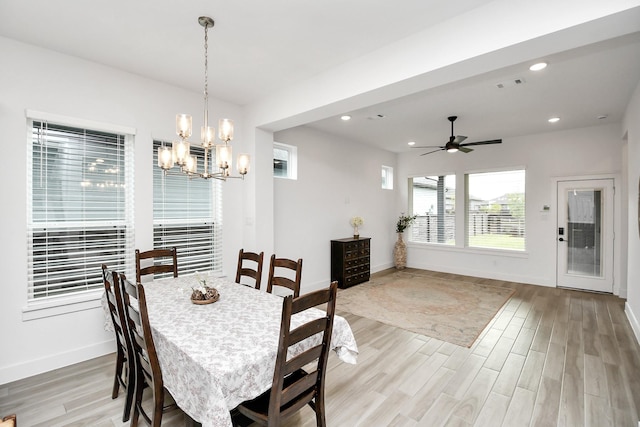 dining space with ceiling fan with notable chandelier and light hardwood / wood-style floors