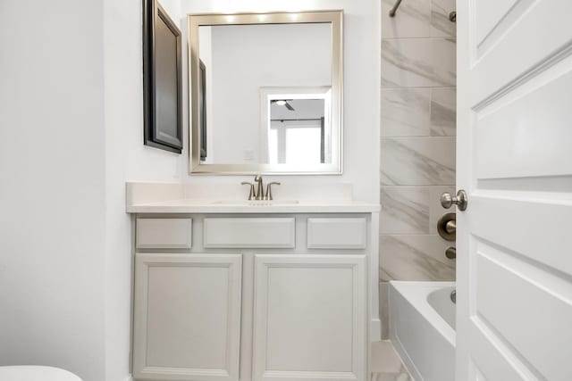 full bathroom featuring vanity, tiled shower / bath combo, and toilet