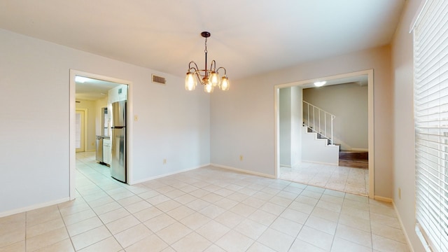 empty room with light tile patterned floors and an inviting chandelier