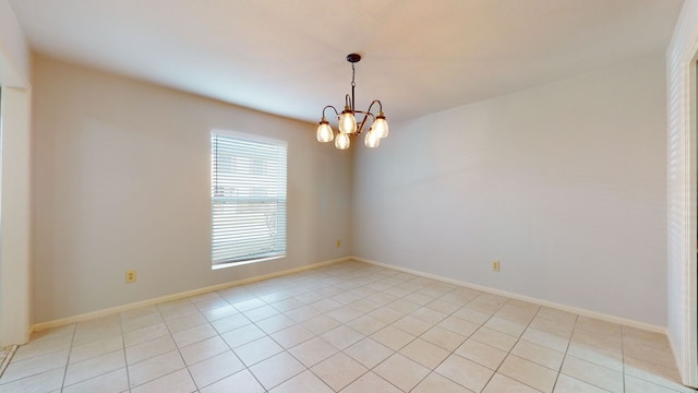 tiled spare room featuring a notable chandelier