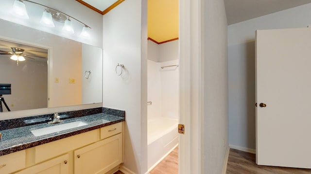 bathroom featuring a tub, ceiling fan, crown molding, wood-type flooring, and vanity