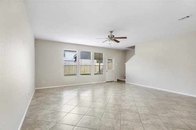 spare room with ceiling fan, light tile patterned floors, visible vents, and baseboards