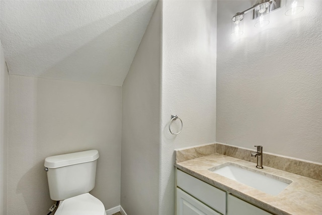 bathroom featuring vanity, vaulted ceiling, toilet, and a textured ceiling