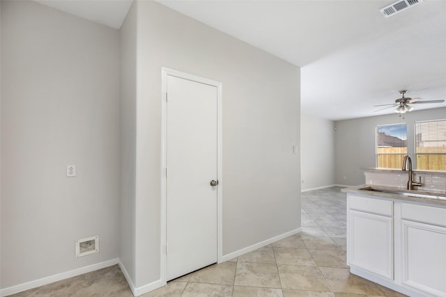 interior space featuring ceiling fan, sink, white cabinets, and light tile patterned floors