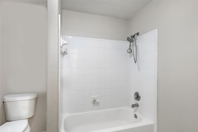 bathroom featuring tiled shower / bath, toilet, and a textured ceiling