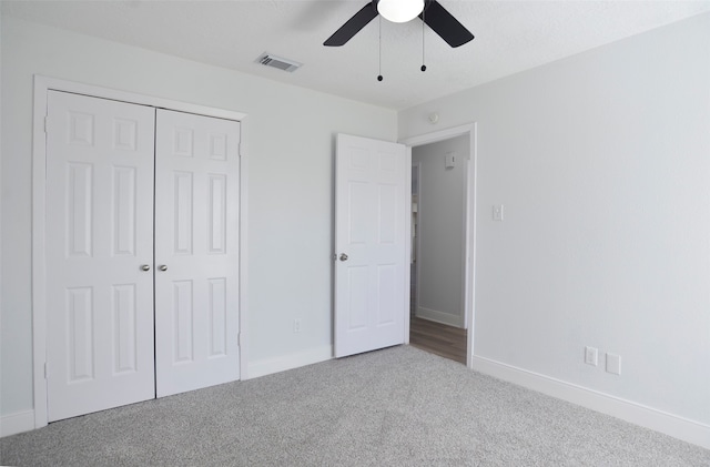 unfurnished bedroom with carpet, a closet, and ceiling fan