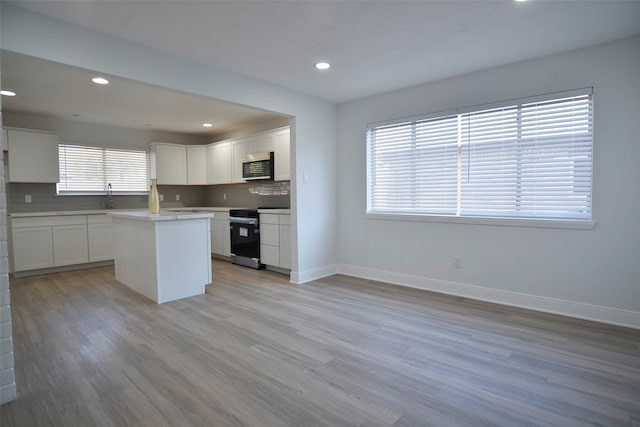 kitchen with plenty of natural light, a kitchen island, stainless steel appliances, and light wood-type flooring