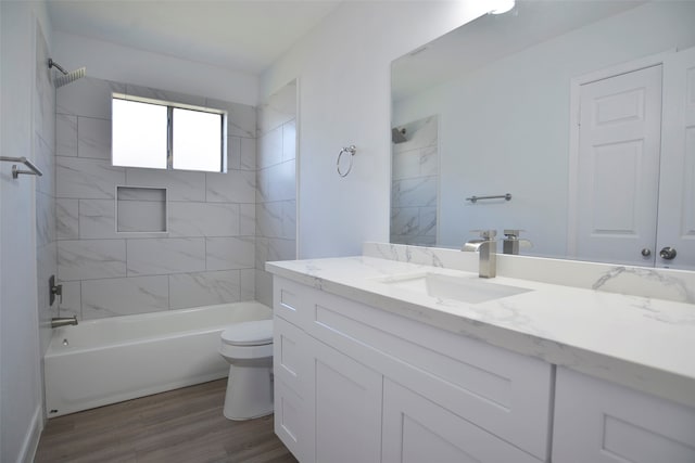 full bathroom featuring hardwood / wood-style flooring, vanity, toilet, and tiled shower / bath